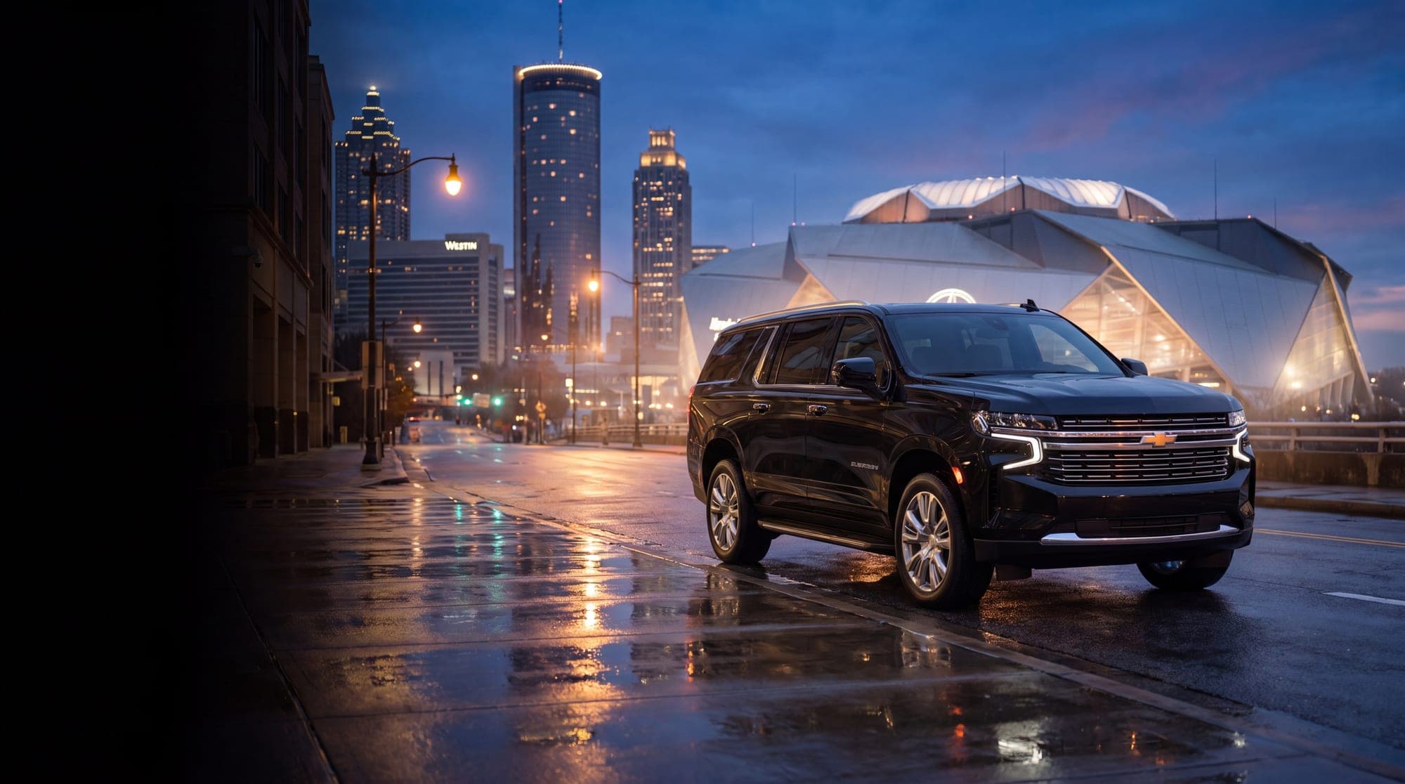 Black Chevrolet Suburban on a downtown Atlanta street at dusk with the city skyline behind it